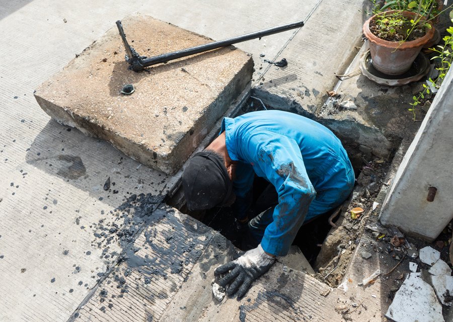 A person maintaining a sewer system by cleaning a drain.