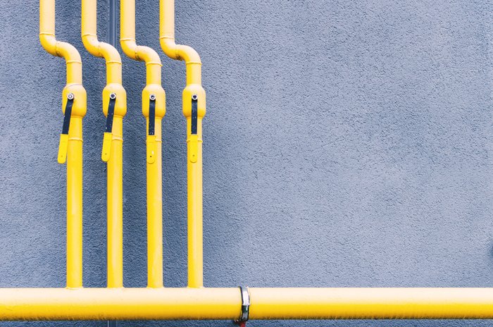 A yellow gas line pipe with four attached pipes.