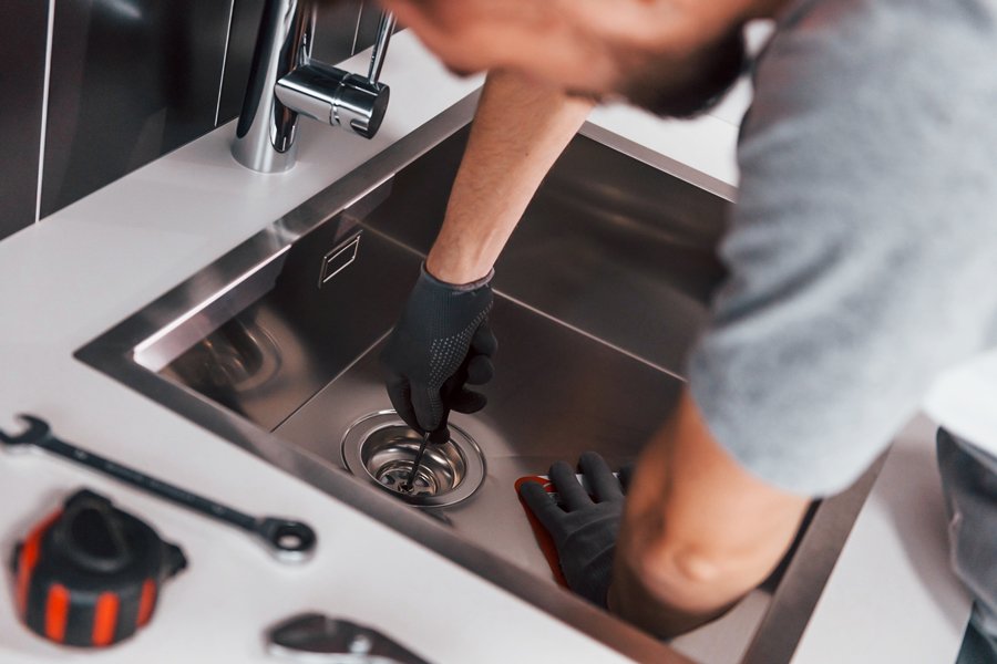 A man working on a sink in a kitchen.