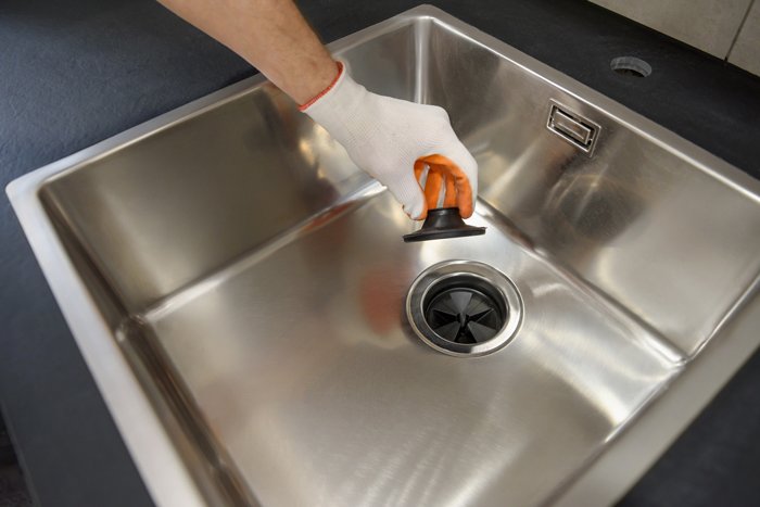 A person cleaning a stainless steel sink