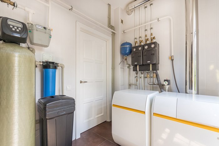 Water heater, toilet, sink, and water treatment equipment in bathroom.