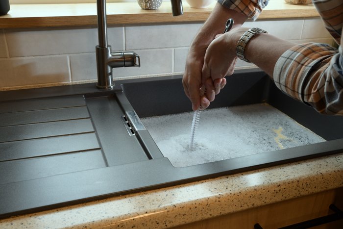 A person washing their hands thoroughly at a sink, emphasizing hygiene and cleanliness in a domestic setting.