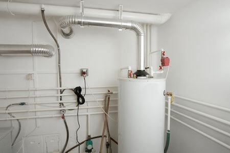 Room with white water heater, pipes, and wires for water heater equipment.