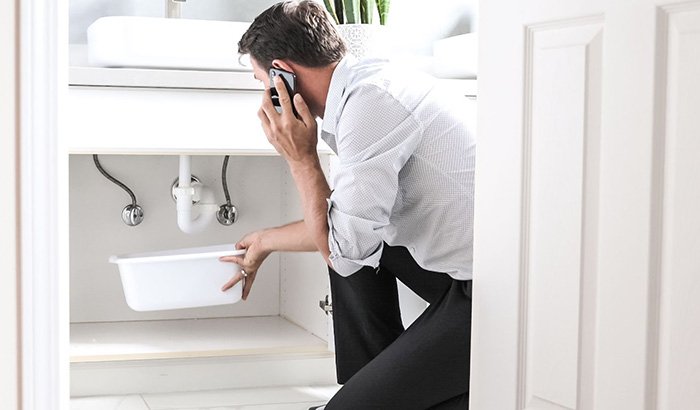 A Man Talking On The Phone In A Bathroom With A Sink