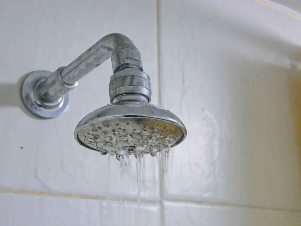 A shower head with water running down it. Contact local plumbing service for plumbing leak repairs and repair services.