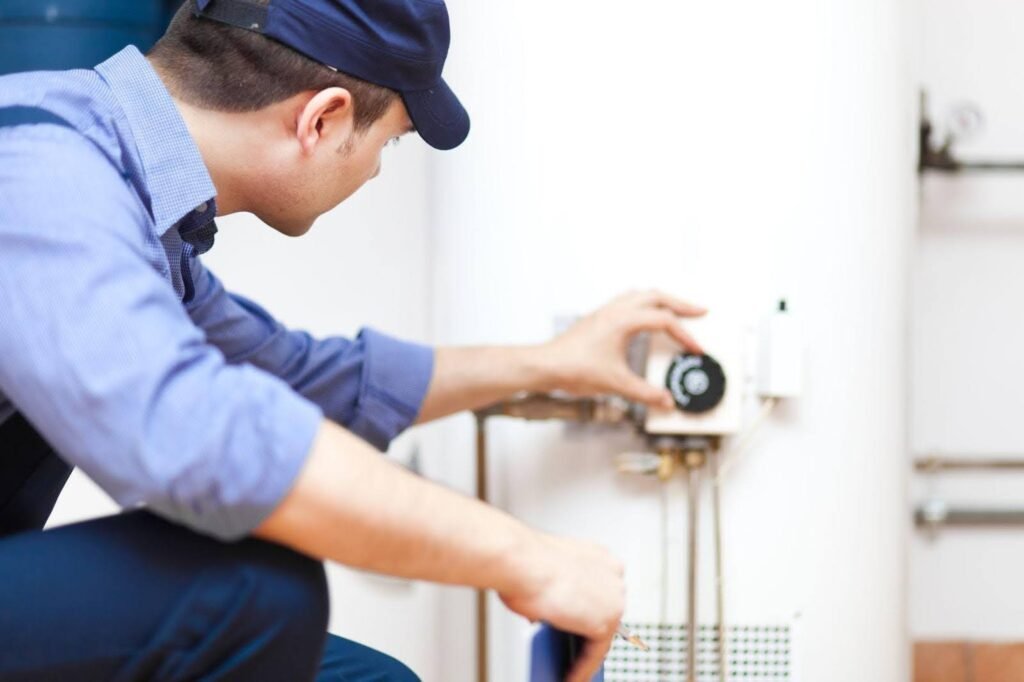 A man in blue overalls repairs a water heater, demonstrating his skills in home maintenance and plumbing