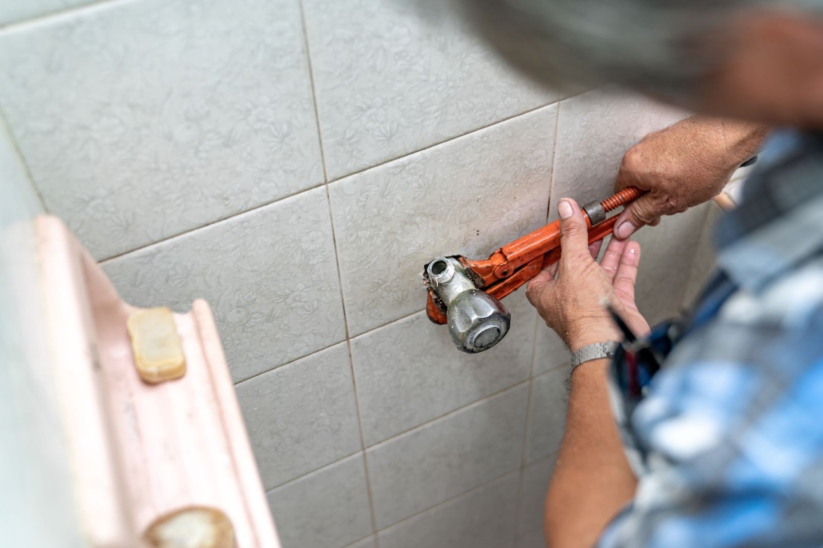 A man using a wrench to repair a toilet, showcasing professional plumbing skills in pipe maintenance.