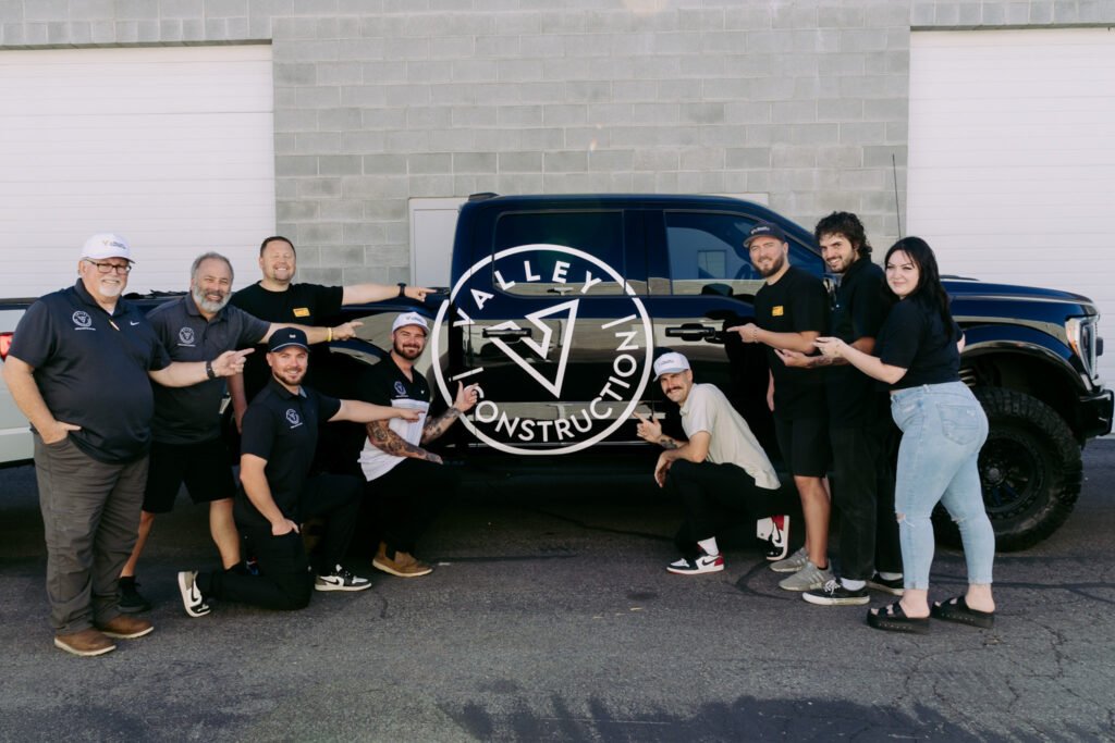 Valley Construction Team Pointing to Raptor Truck with Team Pointing to Valley Construction Logo Photo 1